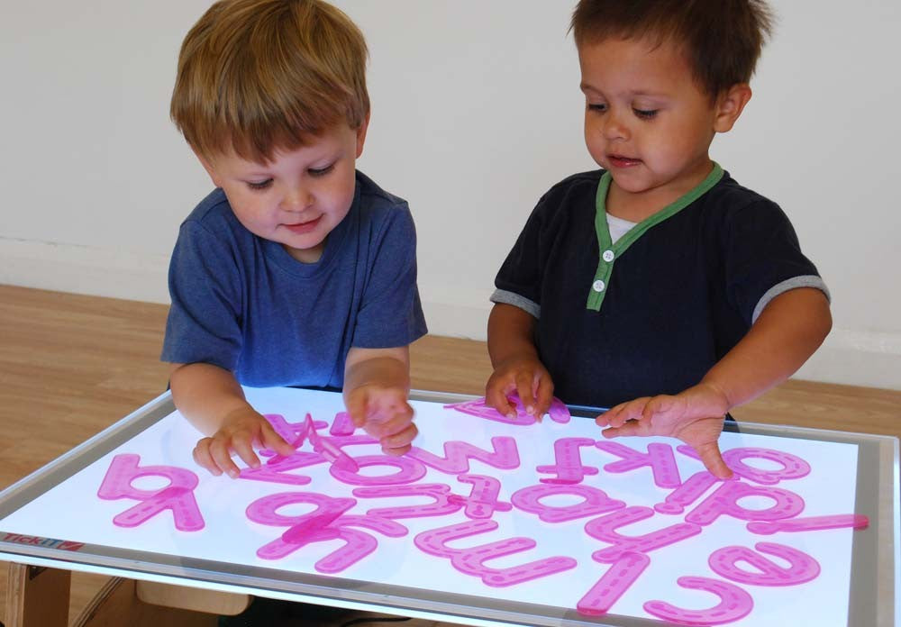 kinderen spelen met de silishapes alfabet letters op een lichtpaneel