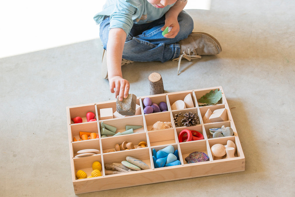 kind speelt met gevulde houten sorteerbak of tinker tray van grapat