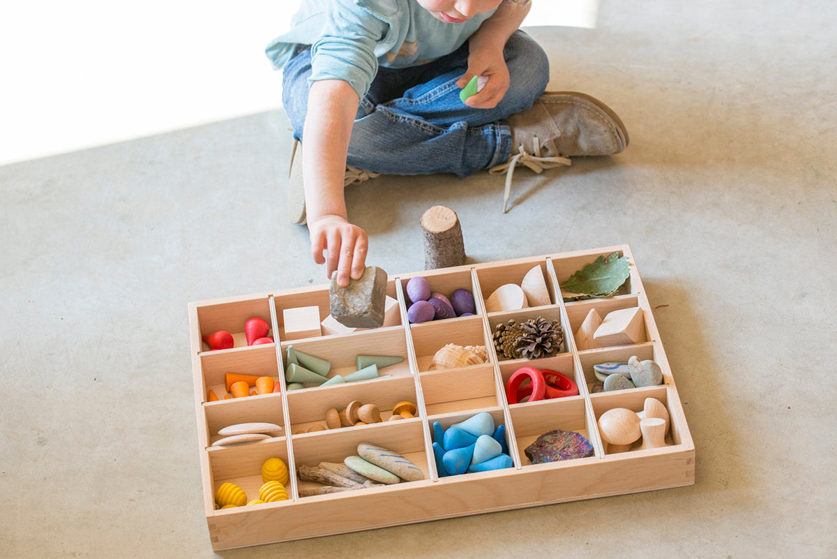 kind speelt met gevulde houten sorteerbak of tinker tray van grapat